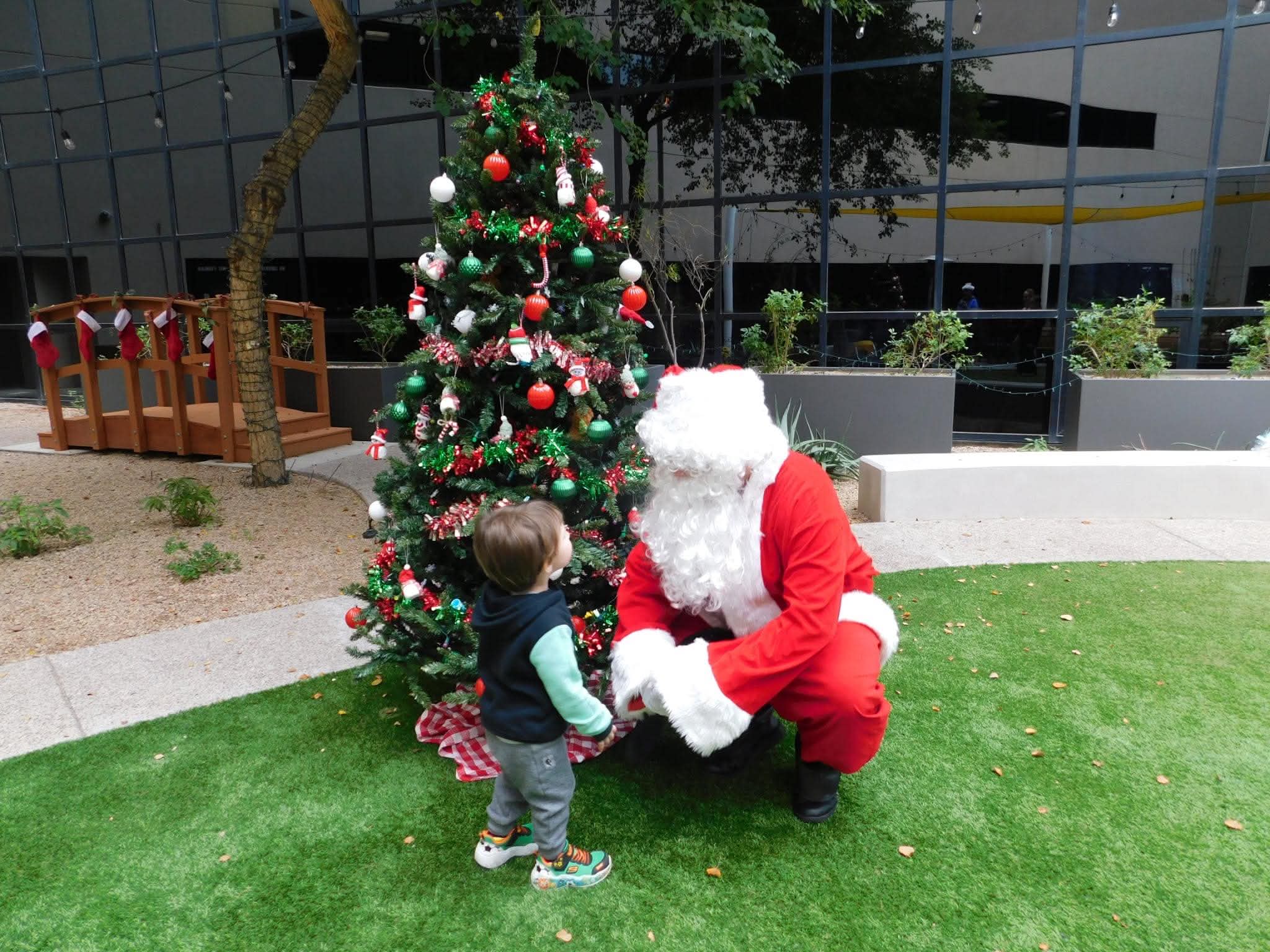 Santa visiting a child beside a Christmas tree